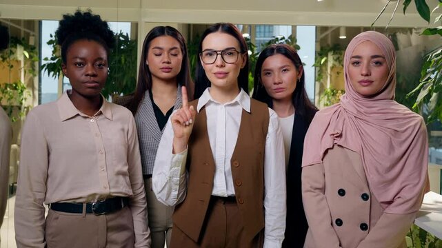 Negative multiethnic women females group five girls coworkers businesswomen business woman looking at camera waving index finger no reject forbid deny disagree risk stop refuse gesture indoors office