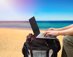 Shot of an unrecognizable digital nomad sitting alone and typing on his laptop during the day at...