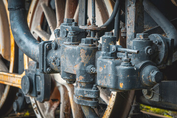metal wheels and the driving mechanism of an old vintage steam locomotive powered by coal. rusty metal and steel. close-up of mechanics and valves