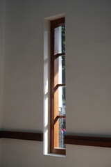 A long window with wooden lines against a white wall exposed to the morning sunlight