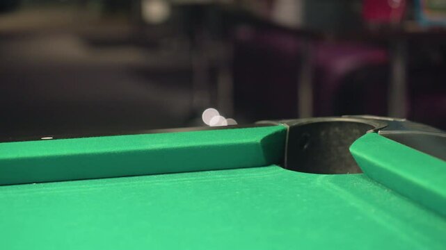 In a blurred background, close-up shot captures red billiard ball rolling rapidly into pool table pocket on green surface. Motion blur highlights speed, accuracy, tension, and competitive excitement