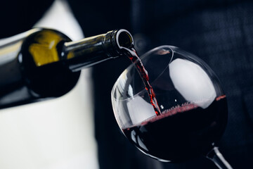 Close-up of red wine being poured into glass by sommelier
