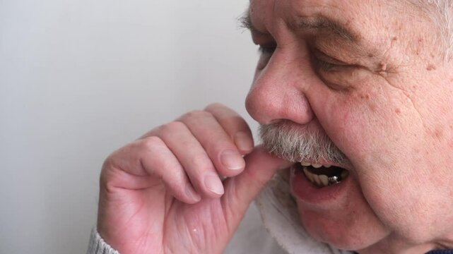 An elderly man holds a denture in his hands. The concept of stomatology and prosthetics. A dental prosthesis. Dentures on hooks