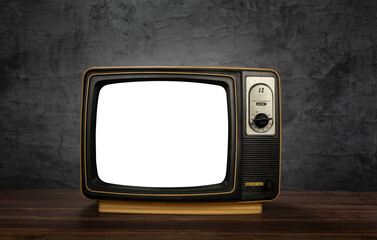 Old vintage television on table in front of wall black background. Classic old obsolete TV, cut white screen