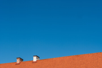 low angle view to a rooftop covered in red clay tiles, against clear blue sky 