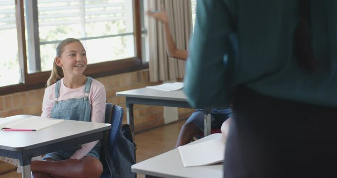 In school, boy raising hand and another boy asking question in classroom