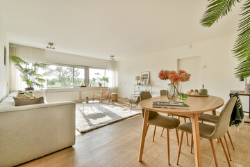 A spacious and stylish living area featuring a light-colored sofa, natural light, and decorative plants, creating a warm, inviting atmosphere.