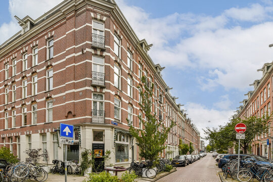 A picturesque view of a brick building amidst greenery, showcasing a serene street scene with bicycles and traffic signs.