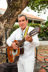 Mature colombian man with a guitar in his hands in the main park of Yaguará - Huila - Colombia....