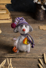 Knitted toy - a gray mouse in a hat with cheese on a wooden background. Crochet interior toys.