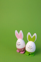 Easter concept with funny bunny and eggs on green background. Easter eggs on green background with copy space.