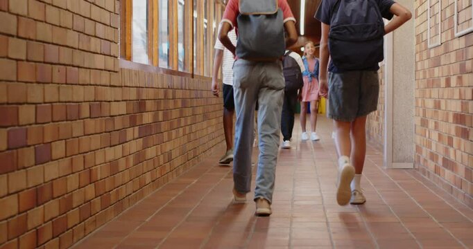 Walking in school hallway, students talking and carrying backpacks with teacher