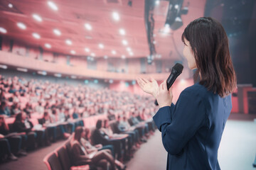 大勢の聴衆が集まるホールで司会をする若い女性