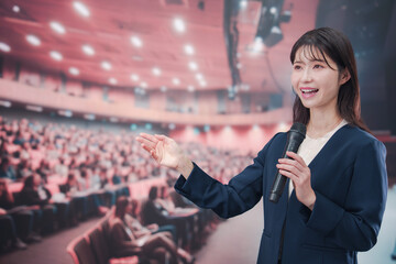 大勢の聴衆が集まるホールで司会をする若い女性
