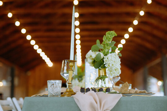 A beautifully arranged dining table featuring decorative flowers, candles, and elegant tableware, perfect for weddings and special occasions.