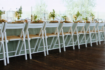A beautifully arranged long dining table with white chairs, adorned with floral centerpieces and elegant decor, perfect for any special occasion.