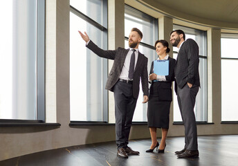 Male realtor showing, real estate agent presenting apartment window, selling, buying property for...