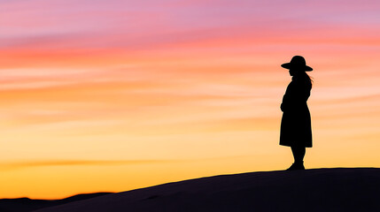 Obraz premium Silhouette of Woman with Hat on Hill at Sunset