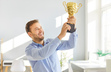 Achievements in business. Businessman celebrates his latest achievement while holding winning...