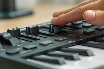 Fototapeta premium Woman playing MIDI keyboard with control knobs and pads, close-up.