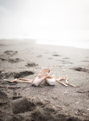 Ballet shoes with ribbons on sandy beach.
