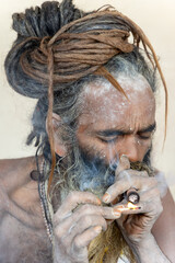 spiritual hindu naga saint lighting marijuana pipe at mahakumbh mela
