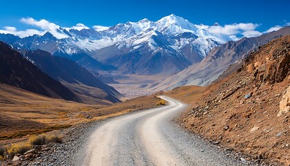 Winding dirt road leads to large mountains under blue skies