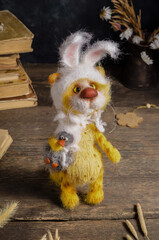 Knitted toy - a yellow cat with bunny ears with a toy duck on a wooden background. Crochet interior toys. Love and Valentine's Day concept.