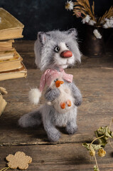 Knitted toy - gray cat with a duck in his hands on a wooden background. Crochet soft toys. Love and Valentine's Day concept.