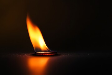 A single flame burns brightly in the darkness