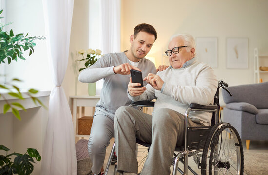 Wheelchair senior man using smartphone app with kind medical brother, consultant nursing, health social care of elderly, doctor male geriatric nurse helping, healthcare hospital for old patient