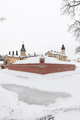Vertical winter landscape photo with a historic castle and bridge. Nesvizh