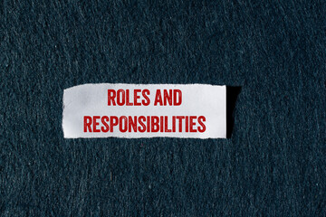 Roles and responsibilities message written on ripped torn paper piece with gray background....