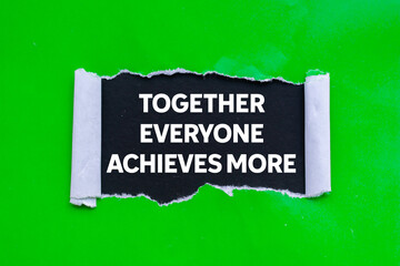 Together everyone achieves more message written on ripped torn green paper on black background. Conceptual together everyone achieves more symbol. Copy space.