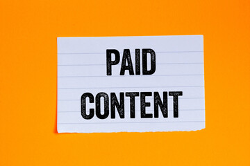 Paid content message written on ripped torn white paper piece on orange background. Conceptual paid content symbol. Copy space.