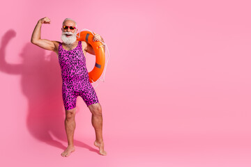 Photo of aged funky man raise hands up winning hold life buoy wear leopard print swim suit isolated pink color background