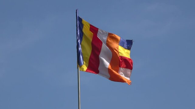 Waving a Buddhist flag against a blue sky. Sri Lanka