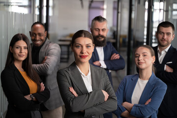 Obraz premium Confident business team standing with crossed arms in modern office, looking at camera. Concept of leadership, teamwork, corporate success, diversity, and professional collaboration