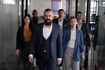 Confident business leader walking with a diverse team in a modern office. Concept of teamwork, leadership, corporate success, business growth, and professional collaboration