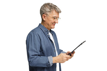 Older man using a tablet while standing indoors, showing focus and engagement with technology