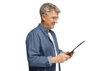 Older man using a tablet while standing indoors, showing focus and engagement with technology