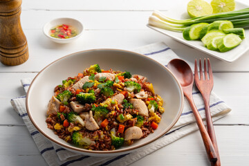 Healthy asian food.Thai fried Organic Red Brown Jasmine Rice (unpolished rice) with chicken breast and broccoli carrot egg in white plate.clean food.