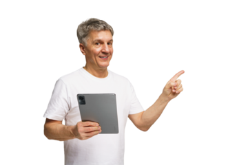 Senior man holding tablet and smiling while pointing with finger in bright indoor space