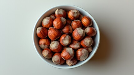 Hazelnuts in white bowl on light background