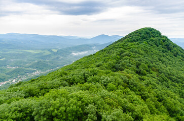 Obraz premium Lush green hill under cloudy sky, overlooking distant landscape
