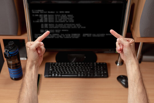 Angry man showing middle fingers to computer screen with system error warning. Man facing monitor, system error message displayed, rear view - Powered by Adobe