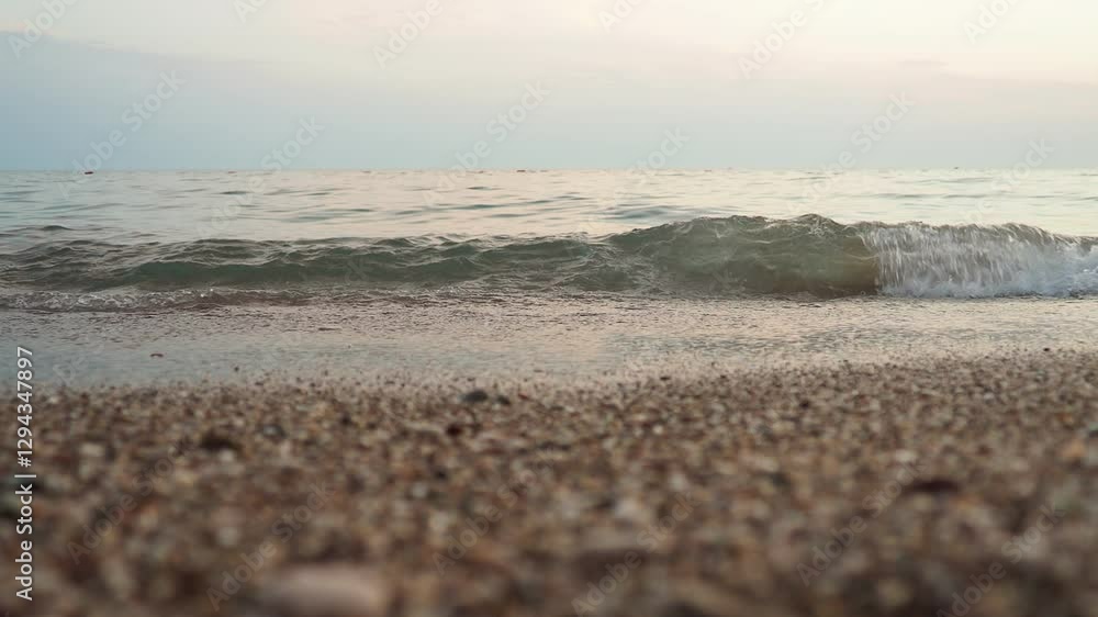 Poster Soft waves roll onto a sandy beach as twilight sets in. The calm sea reflects the fading light, creating a serene atmosphere for evening relaxation. Reflection of rays. Mediterranean Adriatic Sea