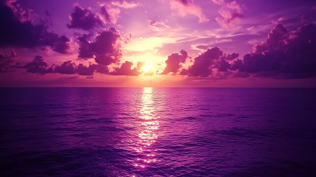 A vibrant sunset sky with deep purple clouds contrasted by a fiery orange glow, casting a striking, dramatic light across the horizon.