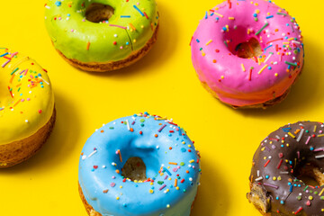 Colorful glazed donuts on yellow background. Top view.
