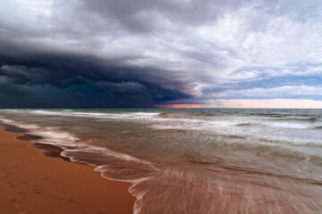 A dramatic storm front looms over the tranquil ocean, contrasting nature's calm and powerful forces.